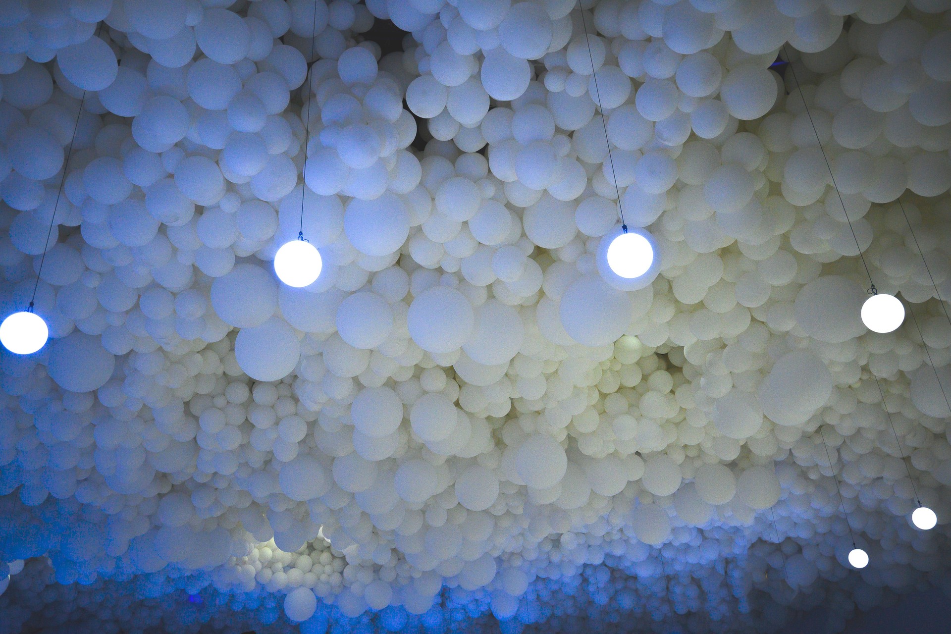 Ceiling of white spheres of numerous balloons with artificial light imitating sky of fluffy clouds